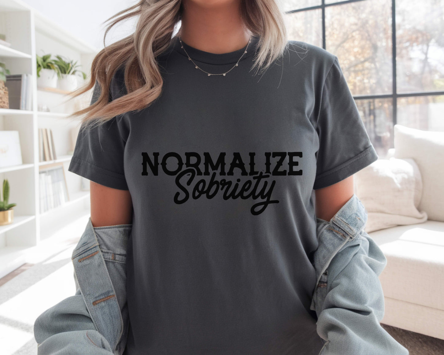 Person wearing a dark gray t-shirt with 'NORMALIZE SOBRIETY' text in a home setting.