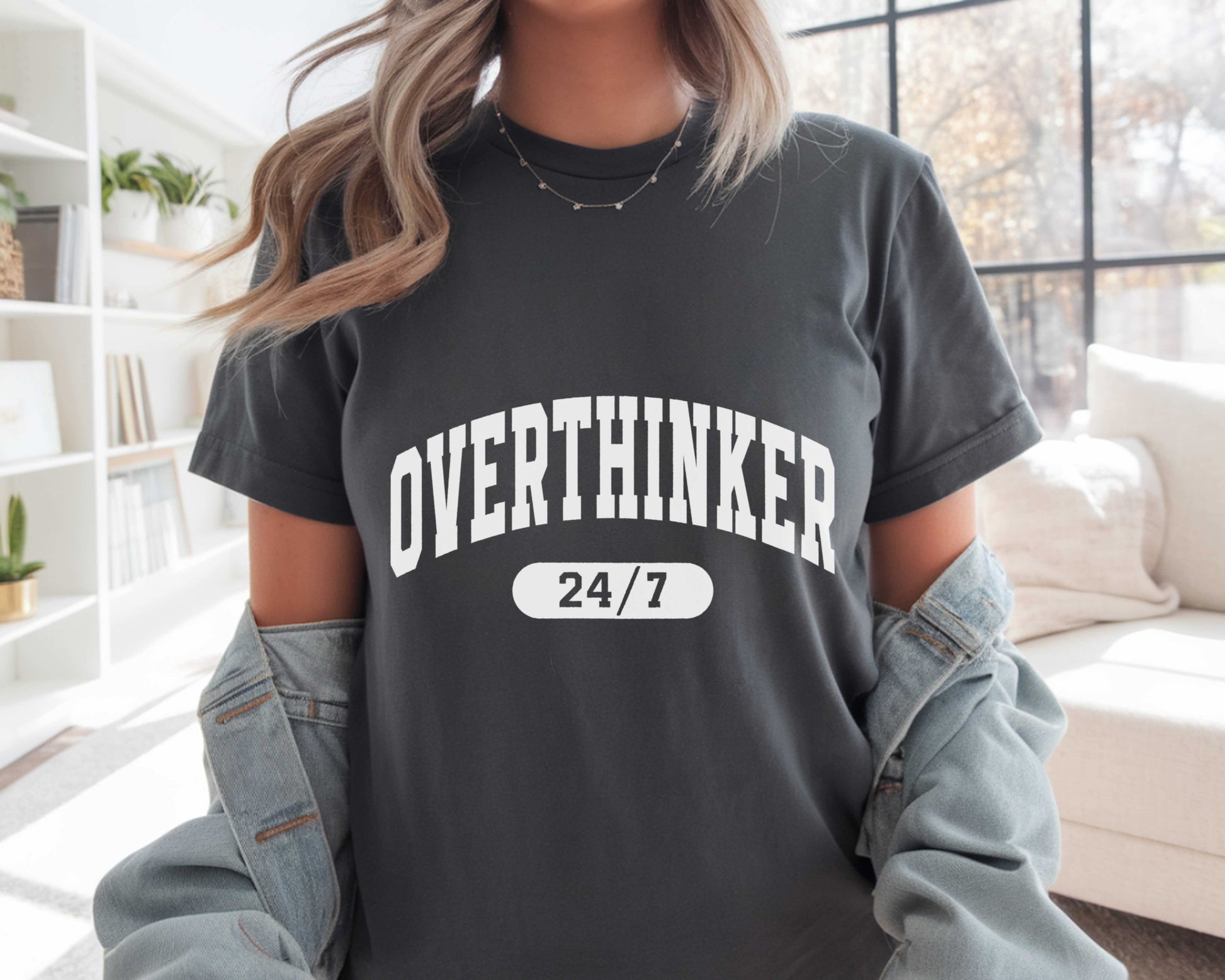 Person wearing a black t-shirt with 'OVER THINKER 24/7' text in a casual setting.