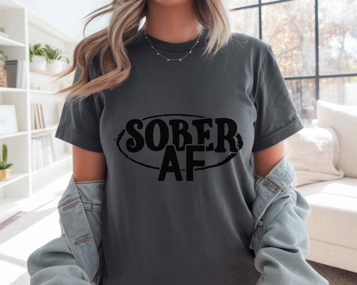 Person wearing a gray t-shirt with 'SOBER AF' text in a living room.