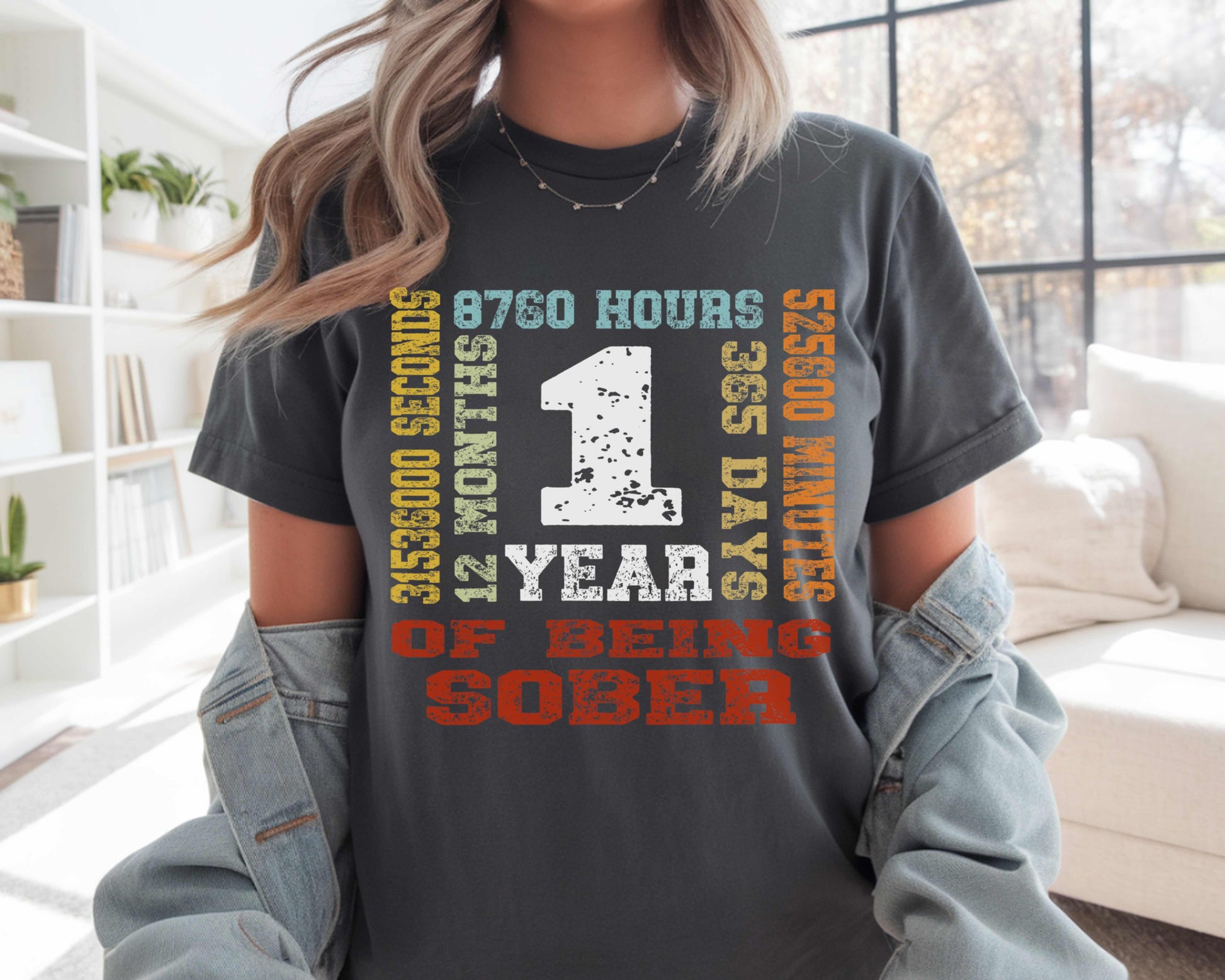 Person wearing a t-shirt with '1 Year of Being Sober' text in a living room.