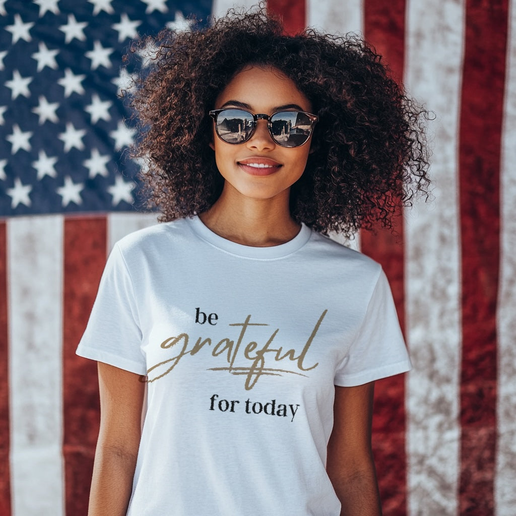 Woman wearing a t-shirt with 'be grateful for today' text in front of an American flag