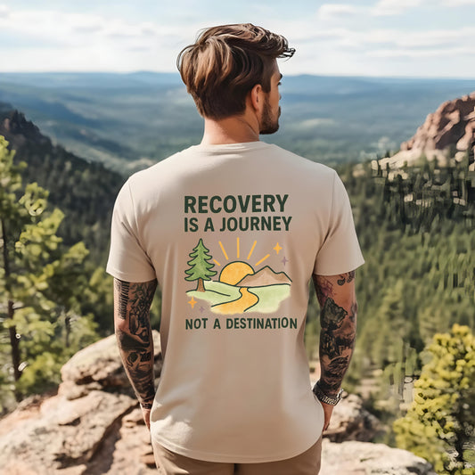 Man wearing a t-shirt with 'Recovery is a Journey, Not a Destination' design on a mountainous landscape.