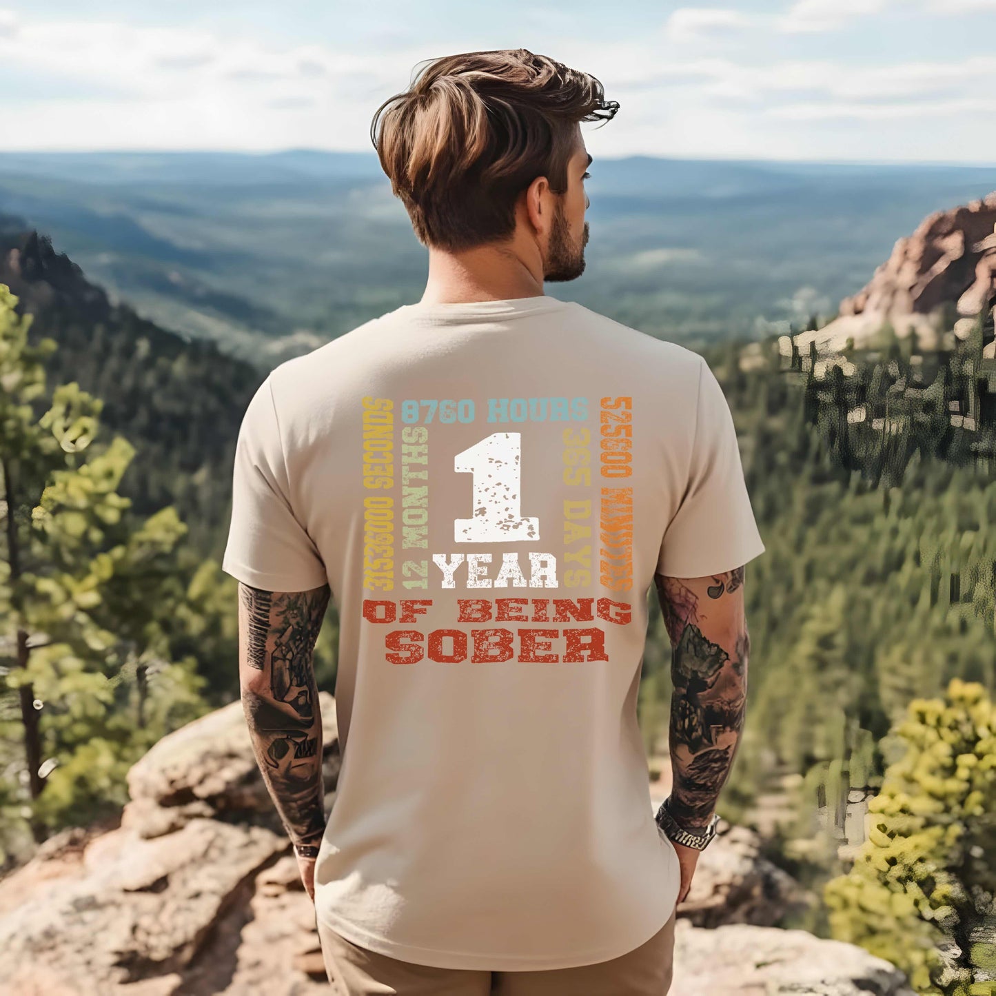Man wearing a t-shirt celebrating one year of sobriety, standing on a scenic overlook.