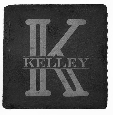 A top view of a slate black square coasters with an engraved design. The coaster features a large, bold letter monogram and the last name horizontally across the middle of the monogram. The engraving is a lighter shade, creating contrast against the dark background of the coaster.