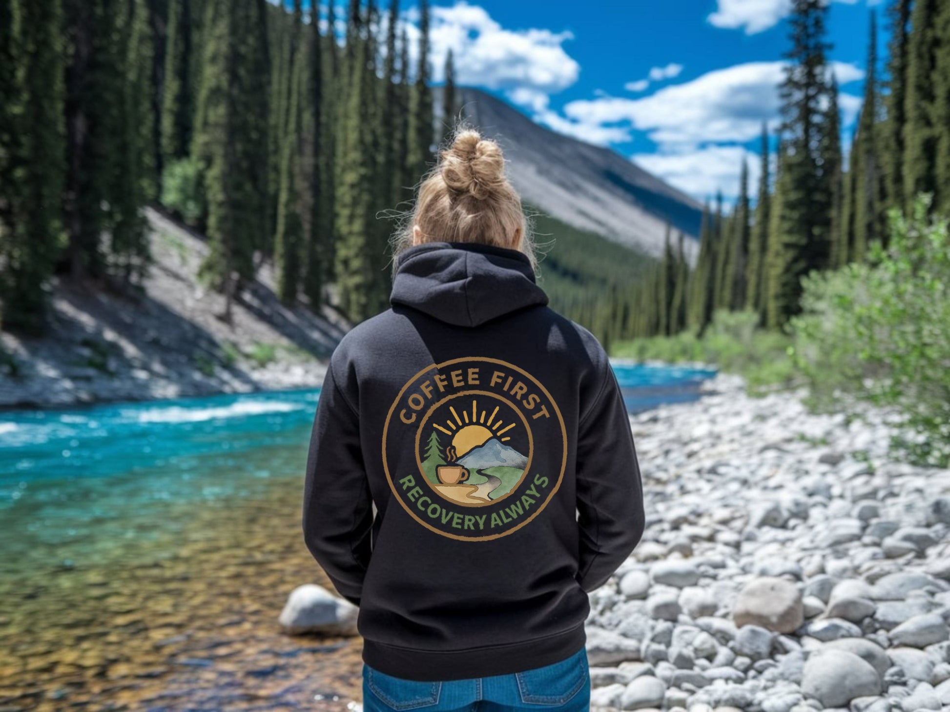 Person wearing a hoodie with 'Coffee First Recovery Always' in a natural setting