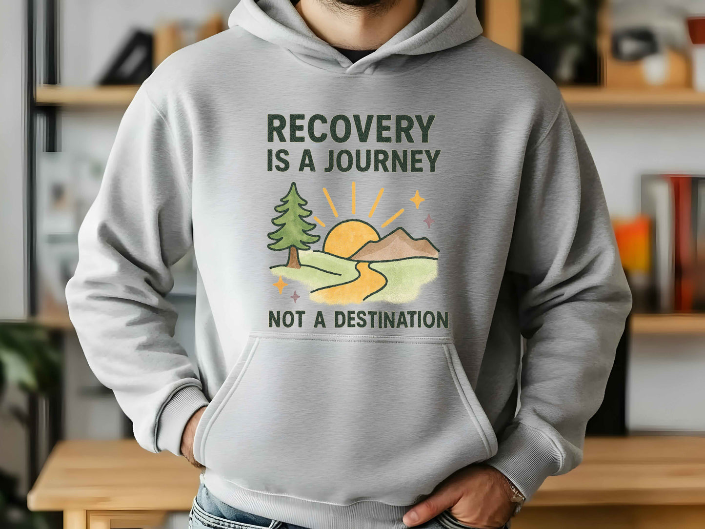 Person wearing a hoodie with 'Recovery is a Journey, Not a Destination' and nature graphic.