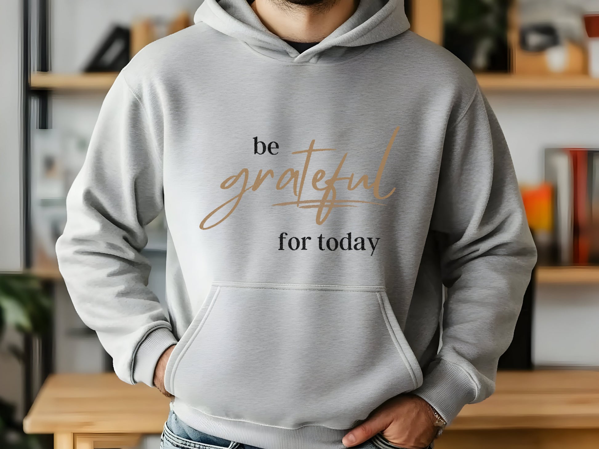 Person wearing a gray hoodie with 'be grateful for today' text in a casual setting.