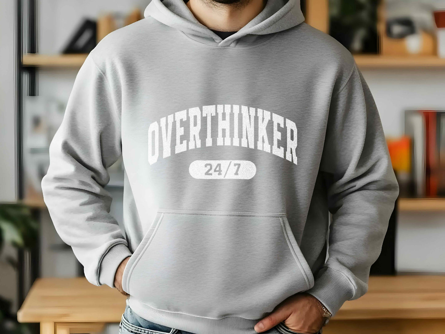 Person wearing a gray hoodie with 'OVERTHINKER 24/7' text in a casual setting.