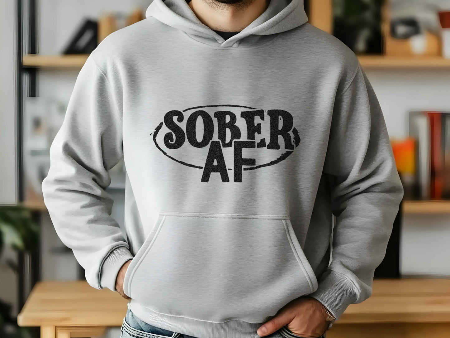 Person wearing a gray hoodie with 'SOBER AF' text in a home setting