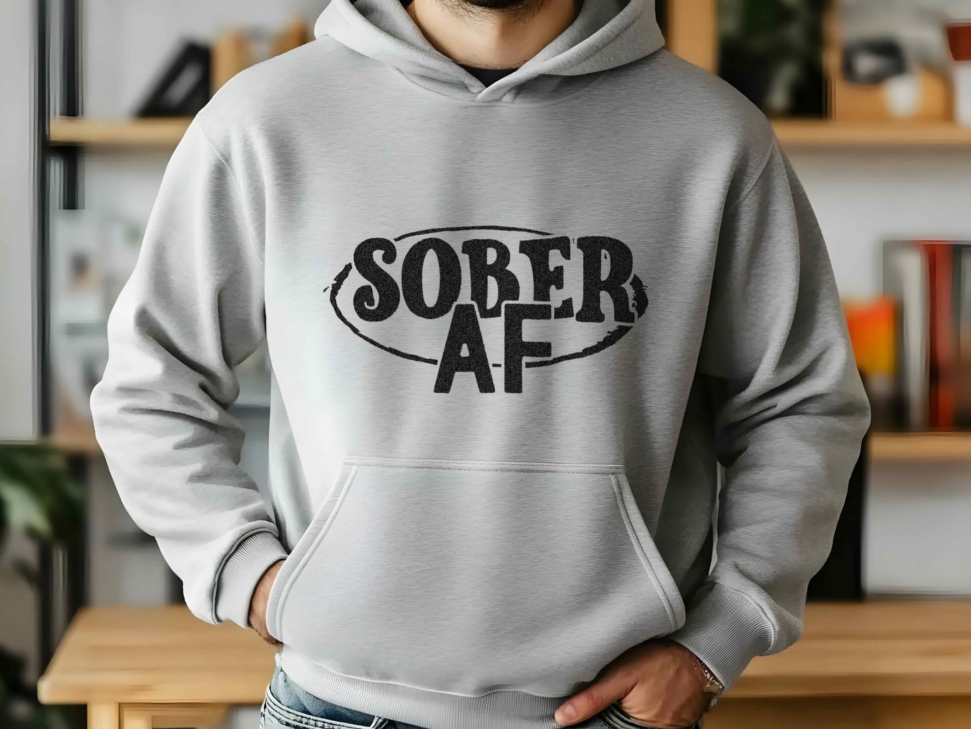 Person wearing a gray hoodie with 'SOBER AF' text in a home setting
