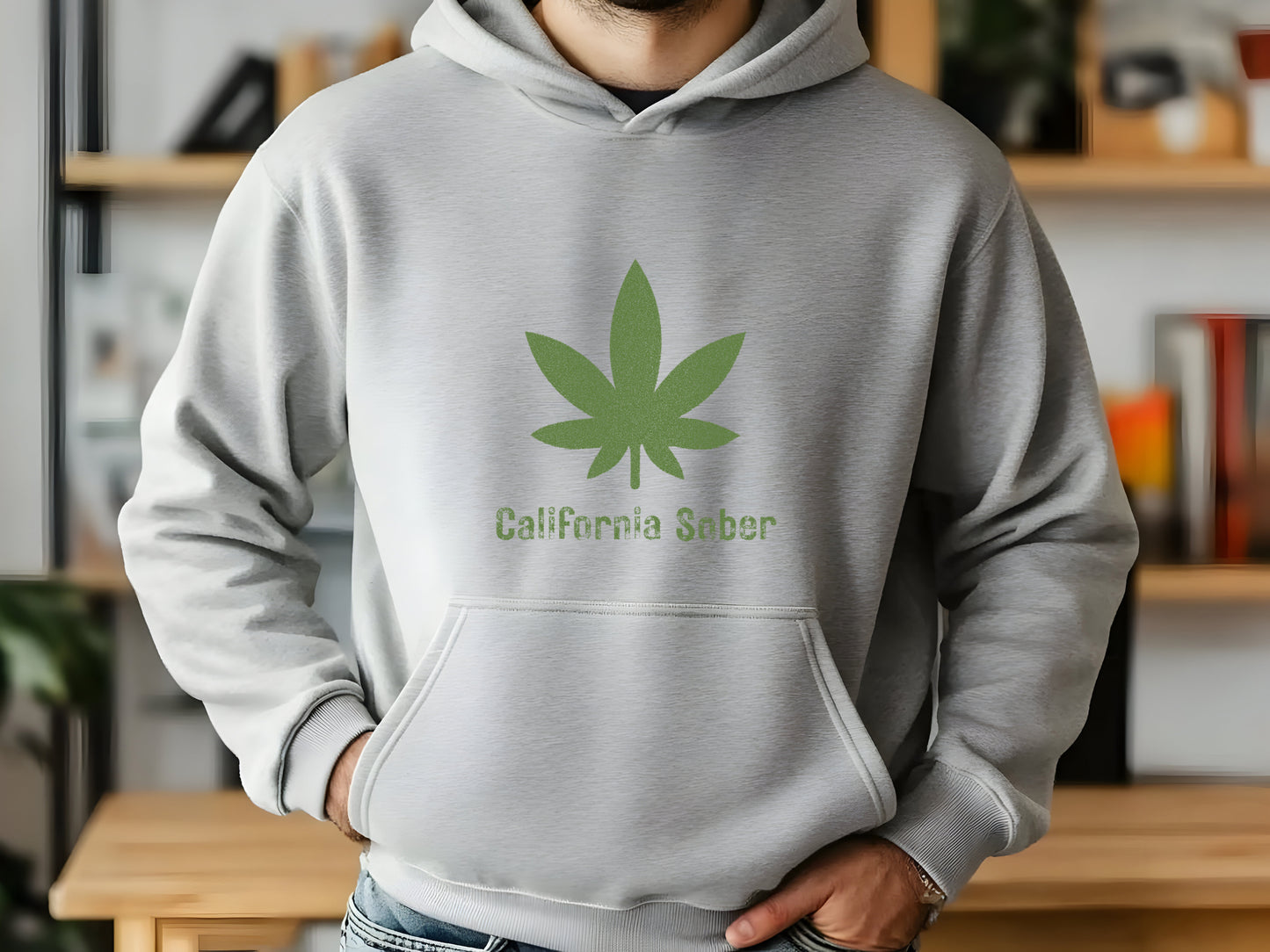 Person wearing a gray hoodie with a green cannabis leaf design and 'California Sober' text.