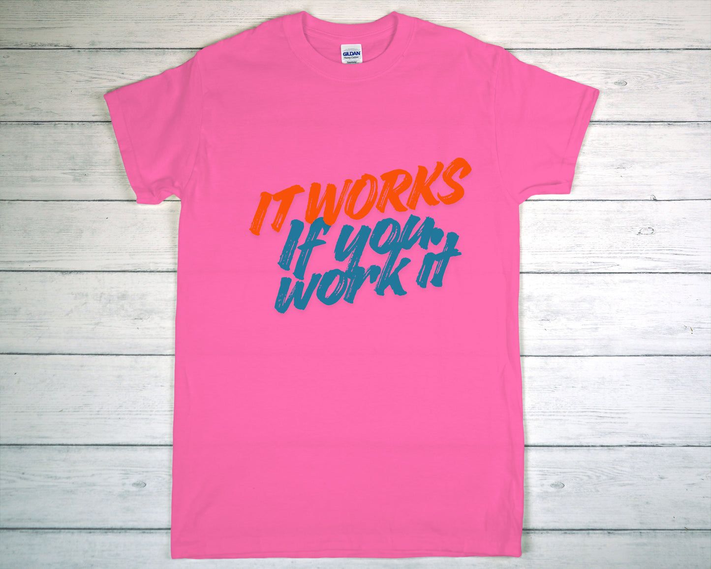 Pink t-shirt with motivational text on a wooden surface