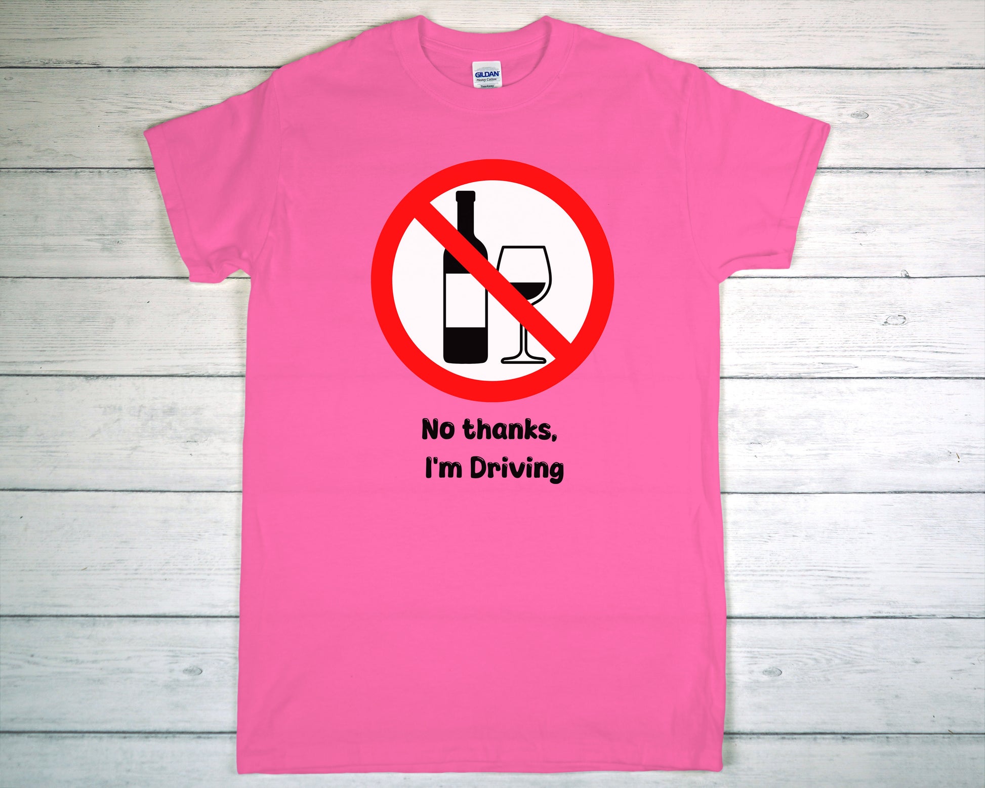 Pink t-shirt with a no drinking while driving symbol on a wooden background