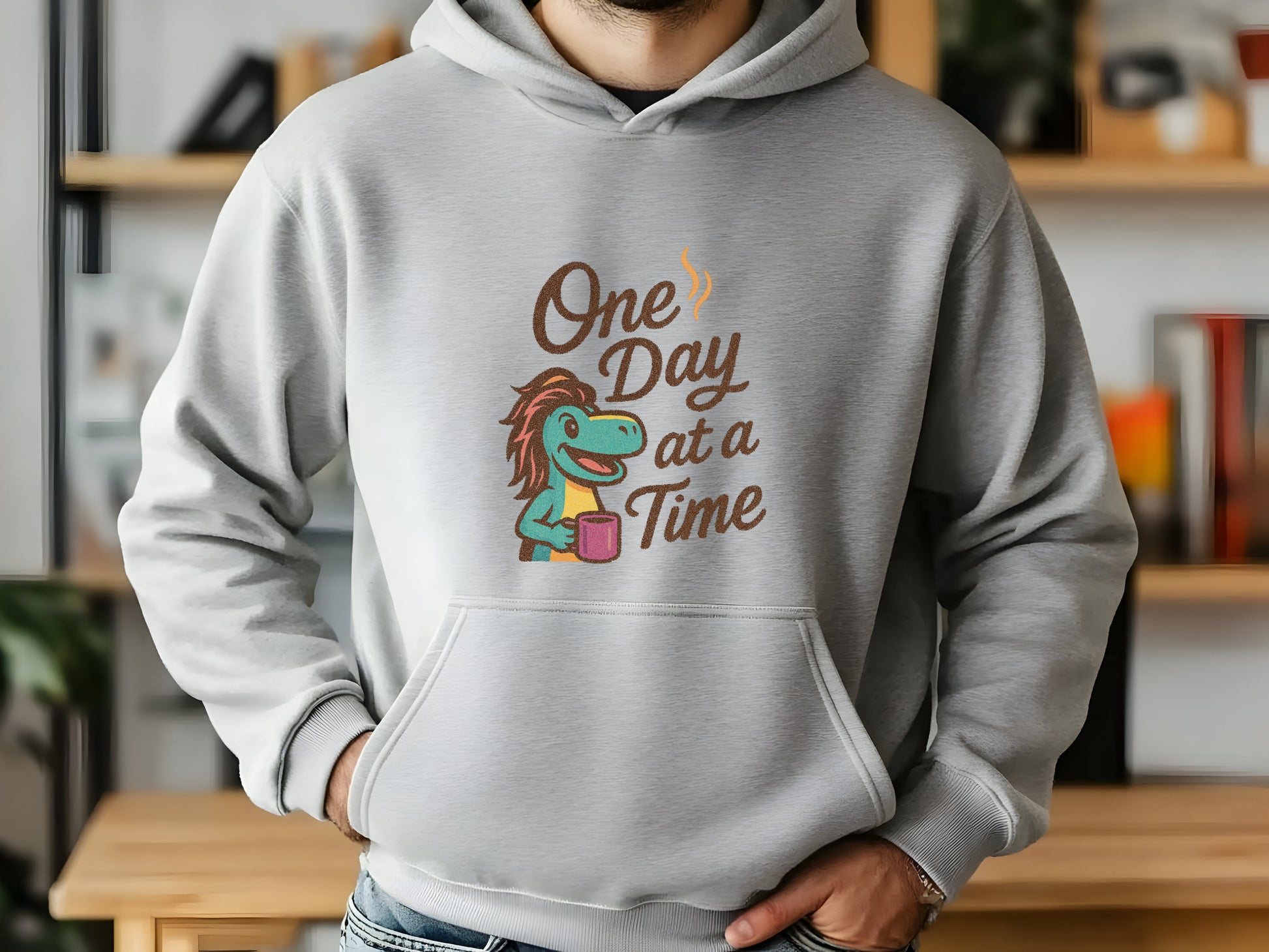 Person wearing a gray hoodie with a graphic design and 'One Day at a Time'  in an indoor setting
