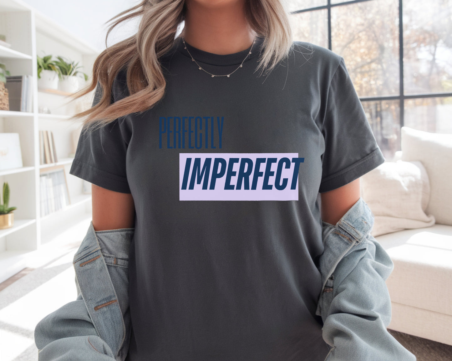 Person wearing a dark gray t-shirt with 'Perfectly Imperfect' text in a living room.