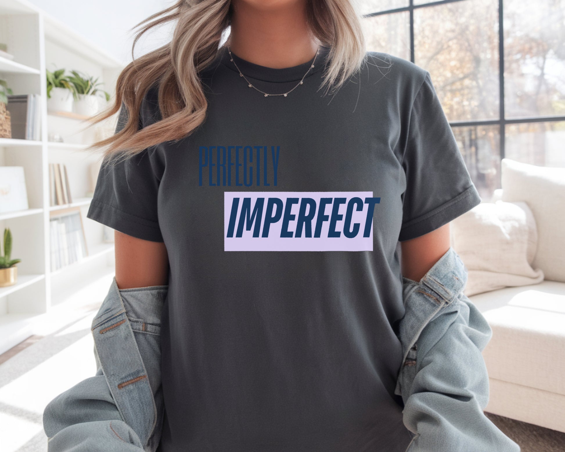 Person wearing a dark gray t-shirt with 'Perfectly Imperfect' text in a living room.