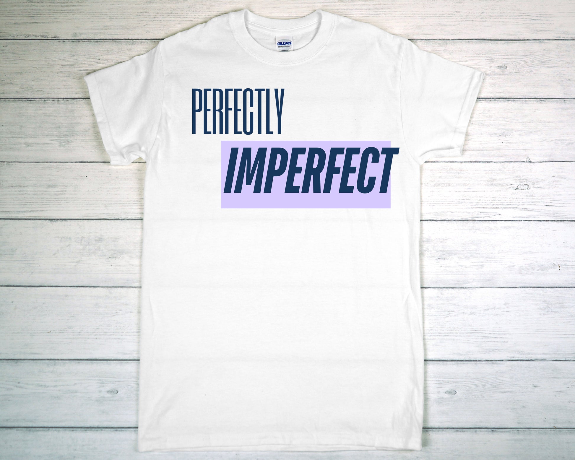 White t-shirt with 'PERFECTLY IMPERFECT' text on a wooden surface