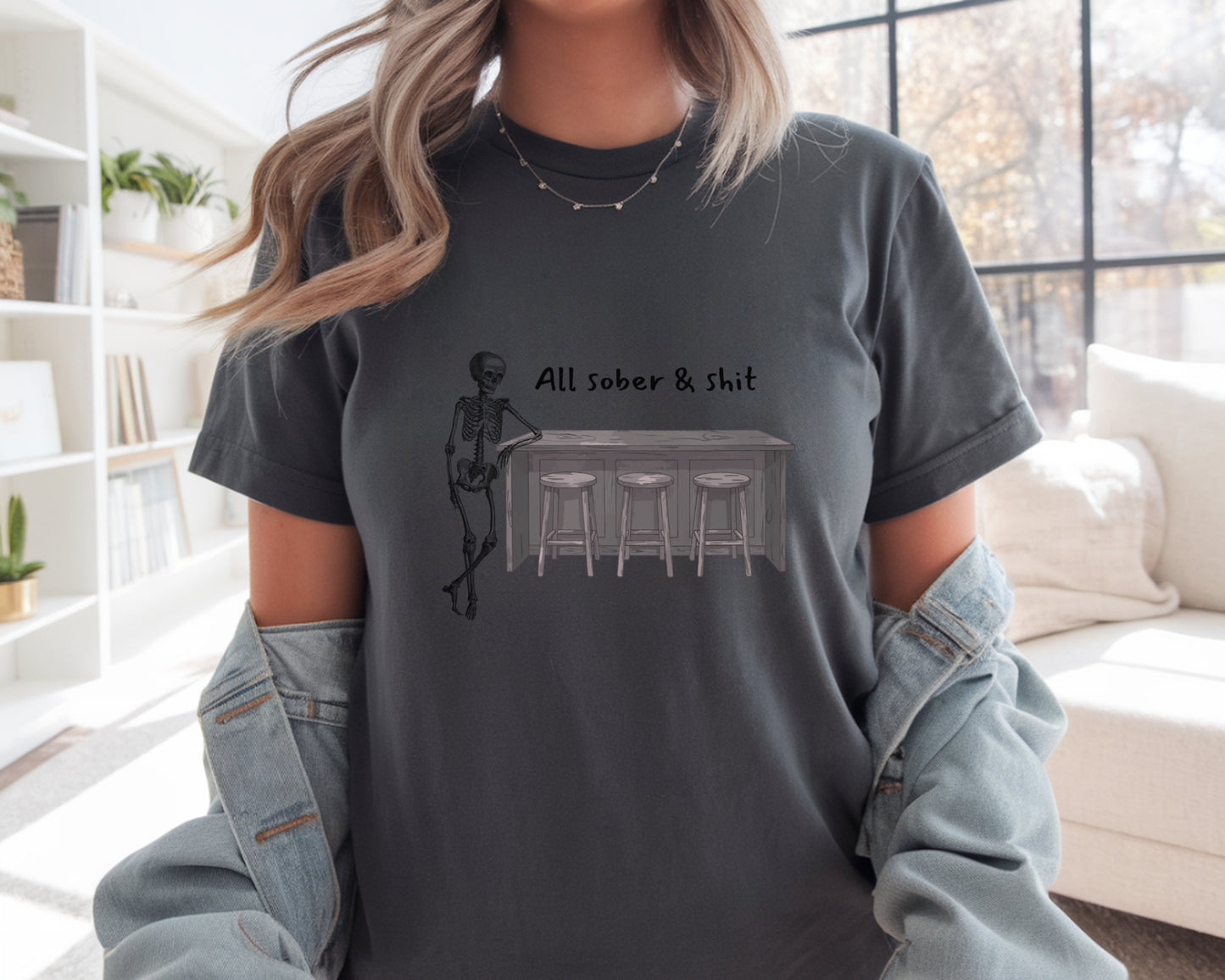 Person wearing a dark gray t-shirt with a graphic design and text in a living room.