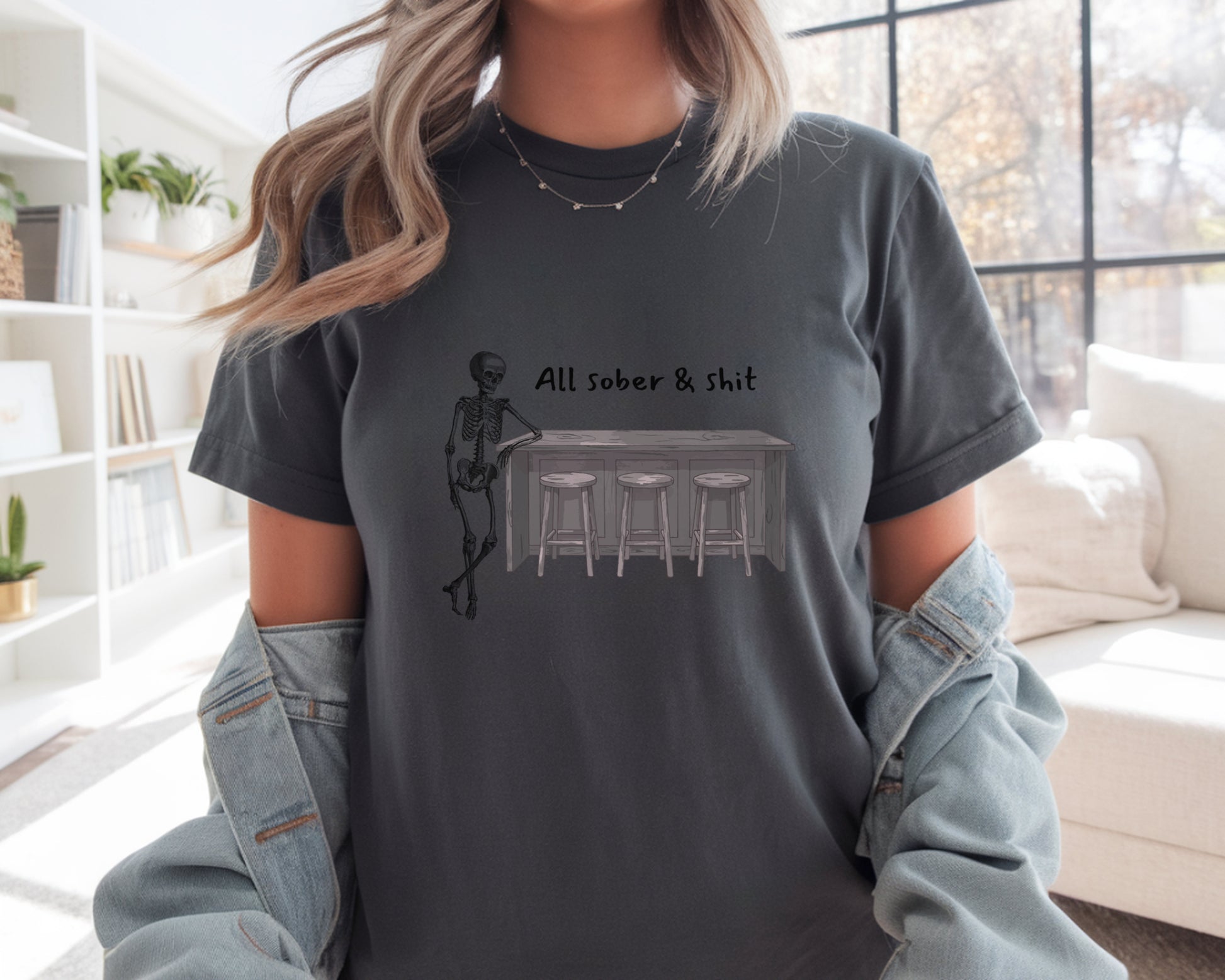 Person wearing a dark gray t-shirt with a graphic design and text in a living room.