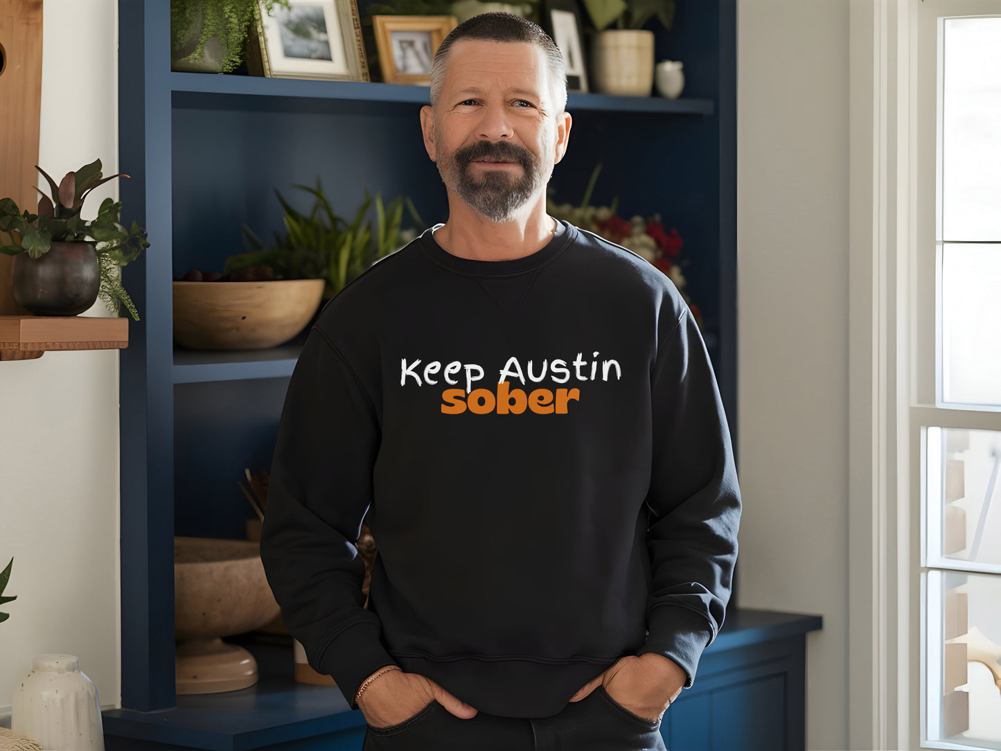 Man wearing a black sweatshirt with 'Keep Austin Sober' text in a home setting